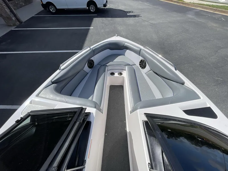 Slide: The Image of 2015 Moomba Mobius LSV boat interior with gray seating and speakers, parked in a lot. - 29