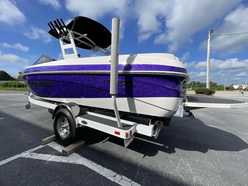 Slide: The Image of 2015 Moomba Mobius LSV boat with purple and white design on a trailer. - 5