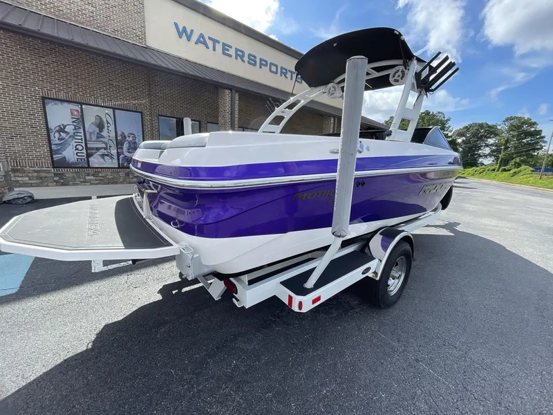 Slide: The Image of 2015 Moomba Mobius LSV boat in purple and white, parked outside a watersports store. - 9