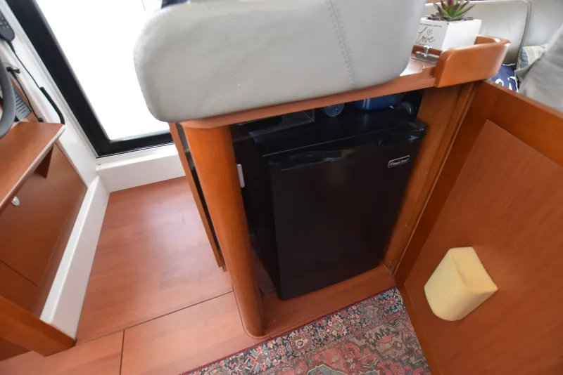 Slide: The Image of Interior of 2019 Beneteau Swift Trawler 44 with compact fridge and wooden cabinetry. - 15