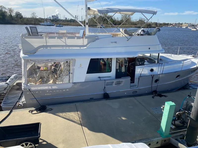 Slide: The Image of 2019 Beneteau Swift Trawler 44 docked by a river, showcasing sleek design and spacious deck. - 2