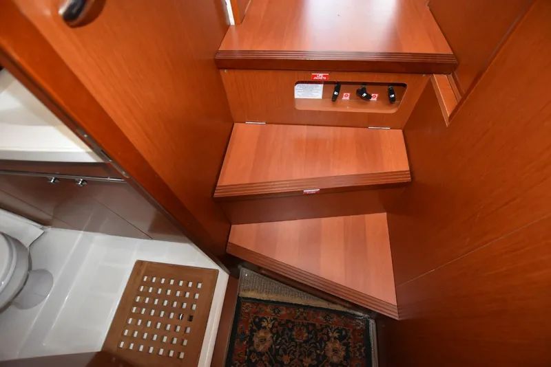 Slide: The Image of Interior stairs of 2019 Beneteau Swift Trawler 44, featuring wooden steps and adjacent bathroom. - 23