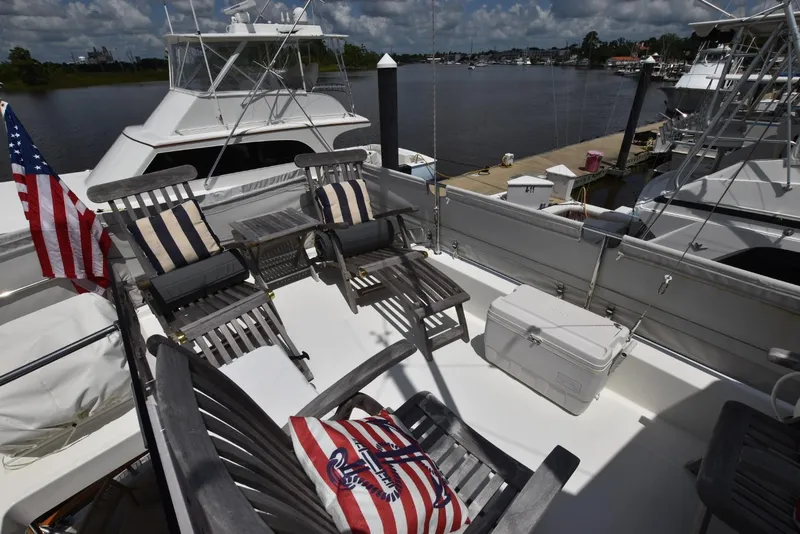 Slide: The Image of 2019 Beneteau Swift Trawler 44 deck with chairs, cooler, and American flag. - 34