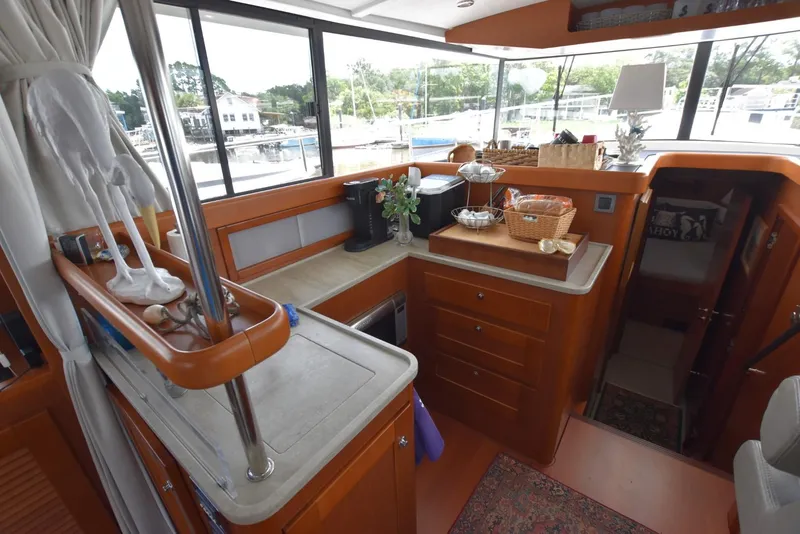 Slide: The Image of Interior of 2019 Beneteau Swift Trawler 44, featuring a compact kitchen with wooden cabinetry. - 7