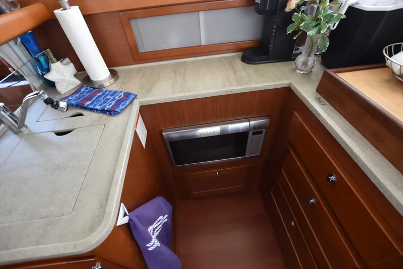 Slide: The Image of 2019 Beneteau Swift Trawler 44 kitchen with microwave, sink, and wooden cabinetry. - 8