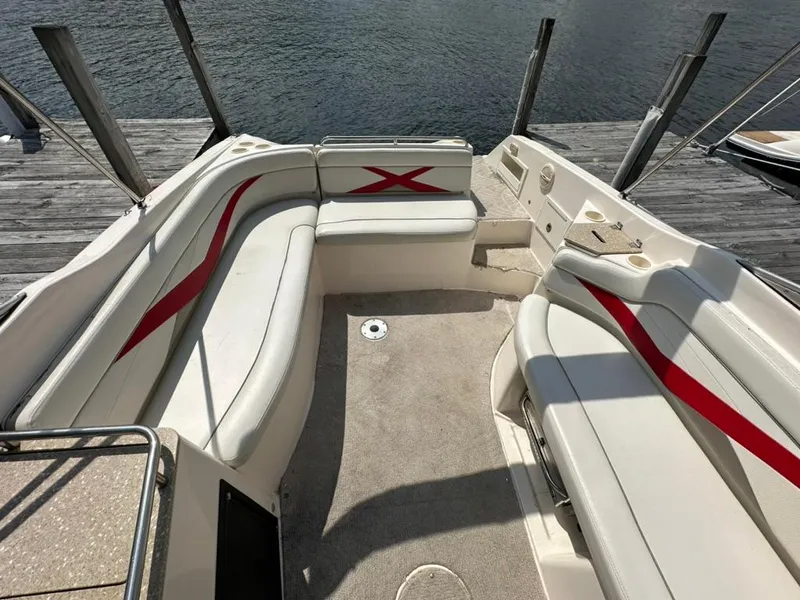 Slide: The Image of 2005 Rinker 282 Captiva Bowrider interior with white seating and red accents by the water. - 10