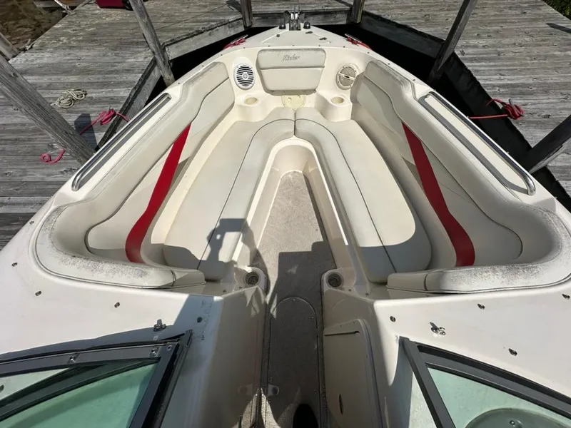 Slide: The Image of 2005 Rinker 282 Captiva Bowrider interior with white and red seating, docked at a wooden pier. - 14