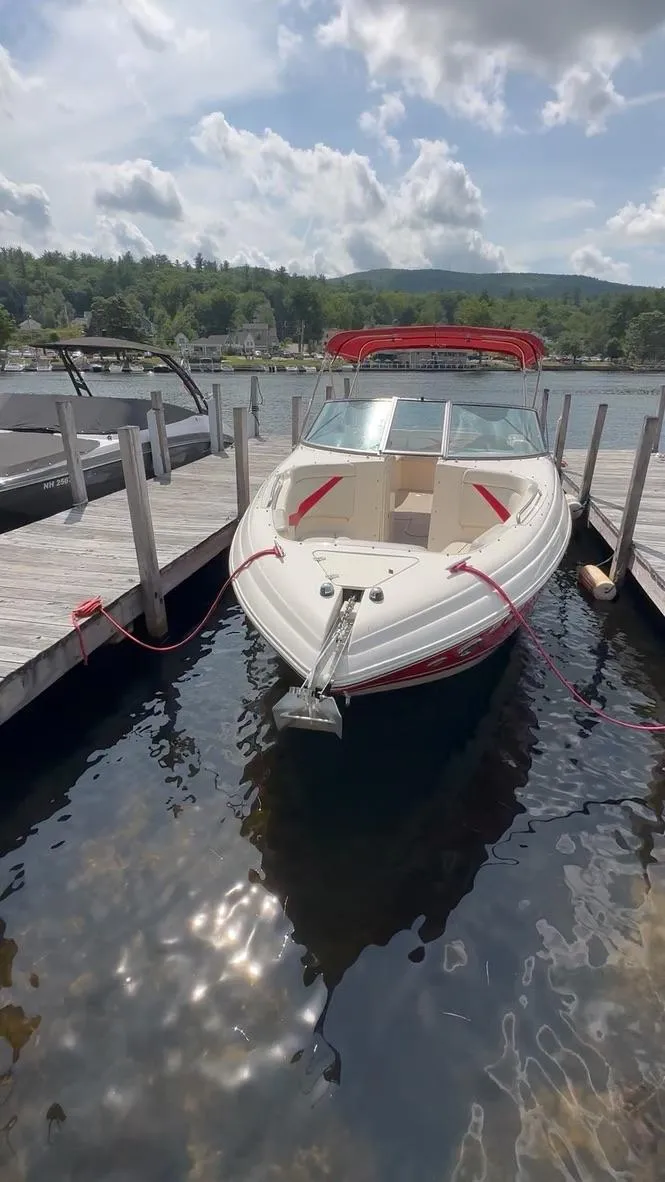 Slide: The Image of 2005 Rinker 282 Captiva Bowrider docked on a sunny day, with scenic lake backdrop. - 19