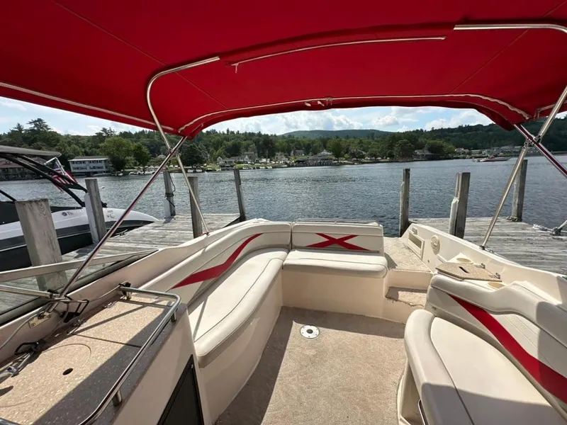 Slide: The Image of 2005 Rinker 282 Captiva Bowrider with red canopy docked by a scenic lake. - 20