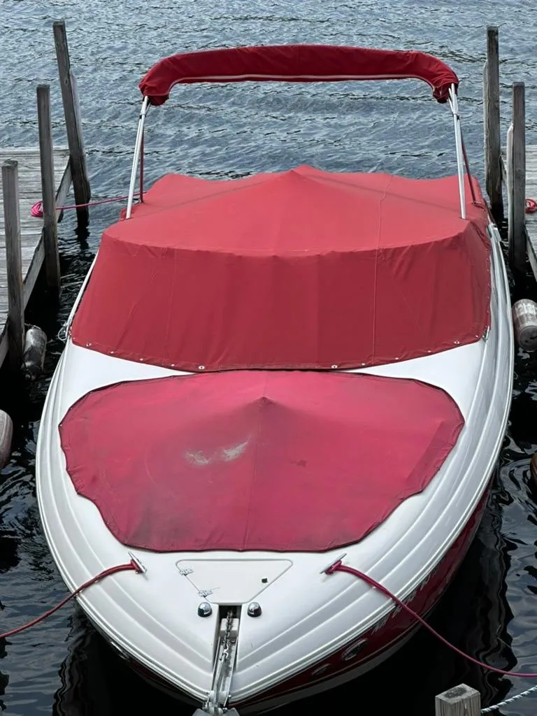Slide: The Image of 2005 Rinker 282 Captiva Bowrider with red cover docked on calm water. - 21