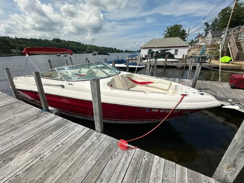 Slide: The Image of 2005 Rinker 282 Captiva Bowrider docked at a lakeside pier under a cloudy sky. - 4