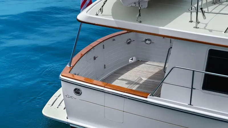 Slide: The Image of 2023 Krogen Express 52 yacht stern with teak deck and railing on blue water. - 22