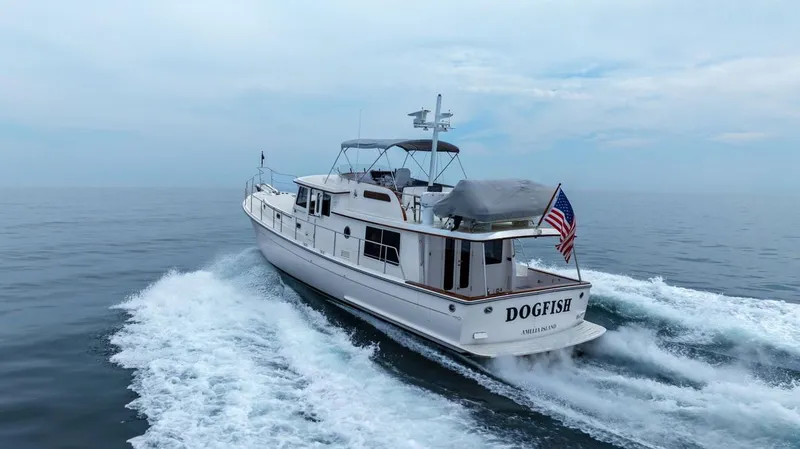 Slide: The Image of 2023 Krogen Express 52 yacht cruising on open water, American flag displayed. - 7