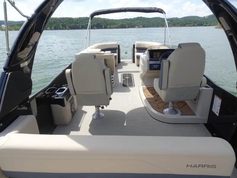 Slide: The Image of 2025 Harris Grand Mariner 250 pontoon boat interior with luxurious seating on a scenic lake. - 7