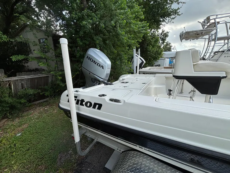 Slide: The Image of 2004 Triton LTS boat with Honda outboard motor, parked near trees. - 2
