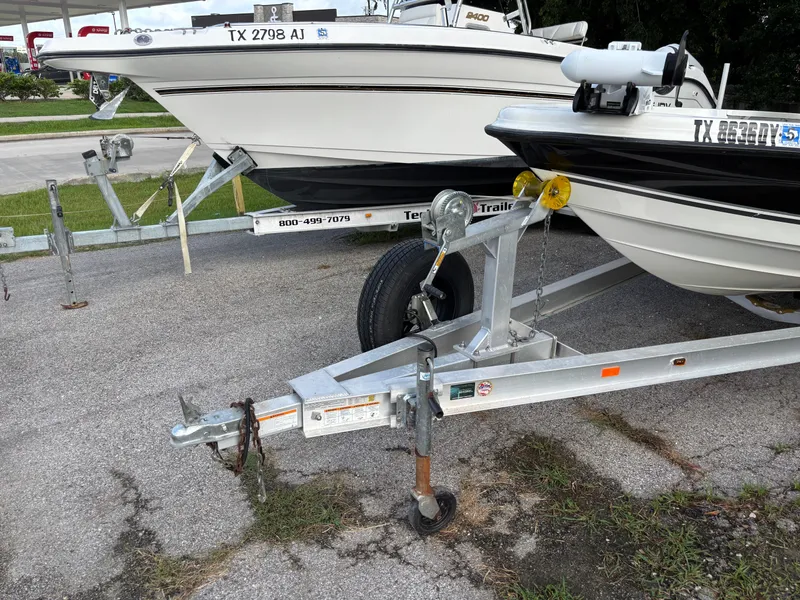 Slide: The Image of 2004 Triton LTS boat on trailer, parked on pavement near grass, with visible license plates. - 22