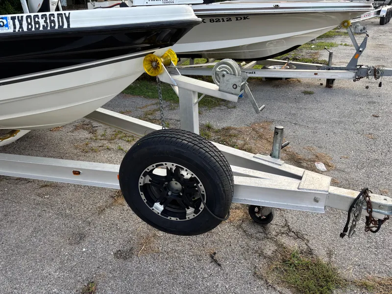 Slide: The Image of Trailer with spare tire for 2004 Triton LTS boat on asphalt surface. - 23