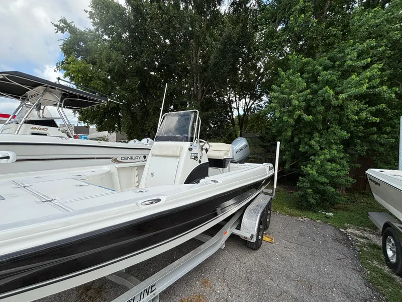 Slide: The Image of 2004 Triton LTS boat on trailer, parked near trees, with Honda outboard motor. - 4