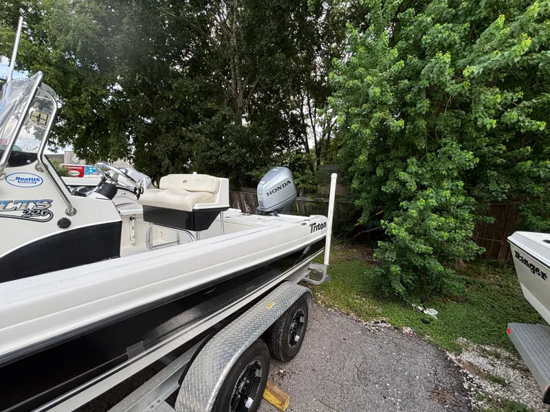 Slide: The Image of 2004 Triton LTS boat on trailer, parked near lush green trees. - 5