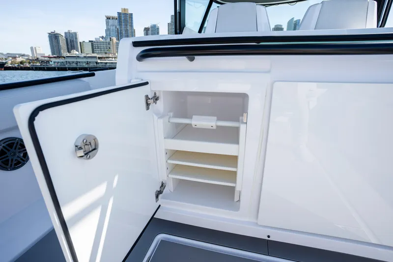 Slide: The Image of Open storage compartment on 2026 Axopar AX29 CCX boat with city skyline background. - 25