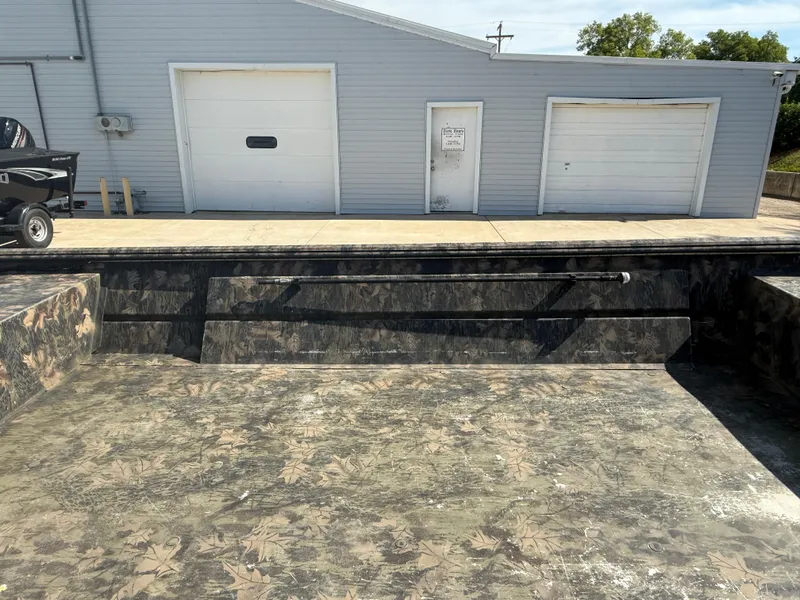 Slide: The Image of 2022 Lowe Roughneck RX2070 Tiller boat with camouflage pattern near a garage. - 10