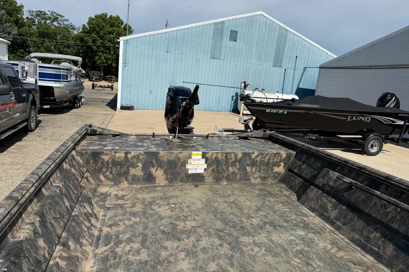 Slide: The Image of 2022 Lowe Roughneck RX2070 Tiller boat with camouflage interior, parked near blue building. - 12