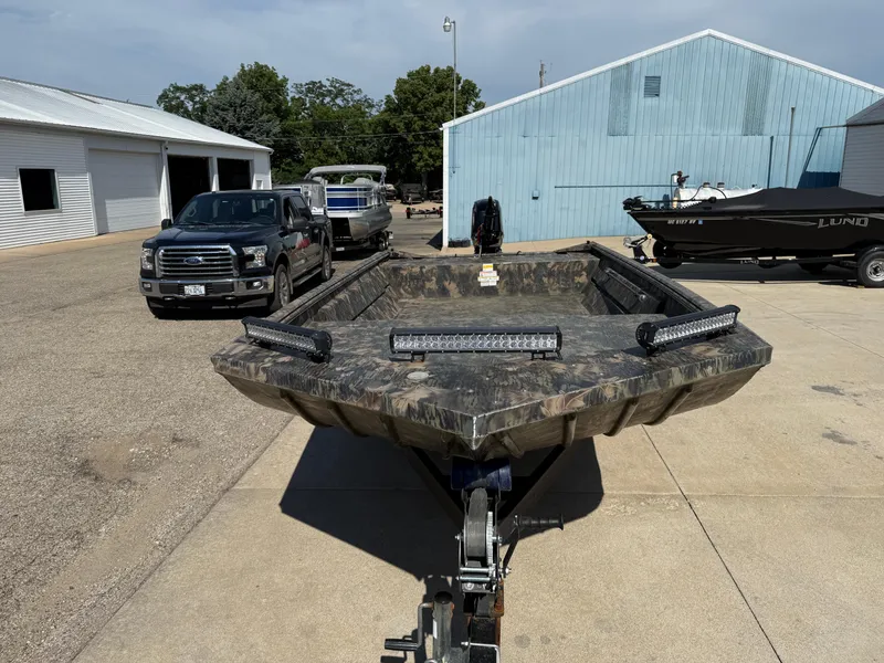 Slide: The Image of 2022 Lowe Roughneck RX2070 Tiller boat on trailer, parked outdoors near buildings. - 2