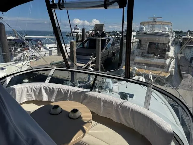 Slide: The Image of 2001 Silverton 35 Convertible yacht interior with marina view, featuring a cozy seating area. - 11