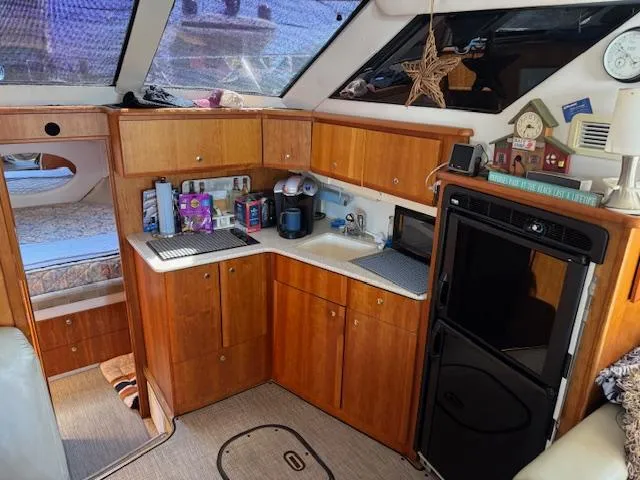 Slide: The Image of 2001 Silverton 35 Convertible yacht interior with kitchen, wooden cabinets, and cozy sleeping area. - 16
