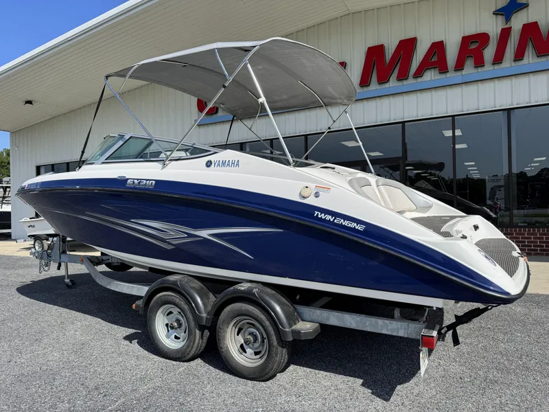 Slide: The Image of 2012 Yamaha SX210 boat with twin engines on a trailer outside a marine store. - 3