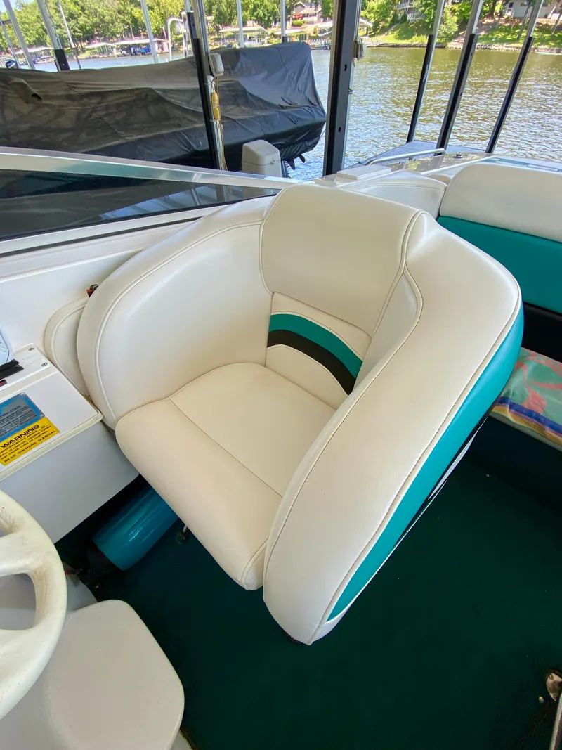 Slide: The Image of White and teal boat seat on a 1999 Checkmate 259 Convincer, near a lake. - 15