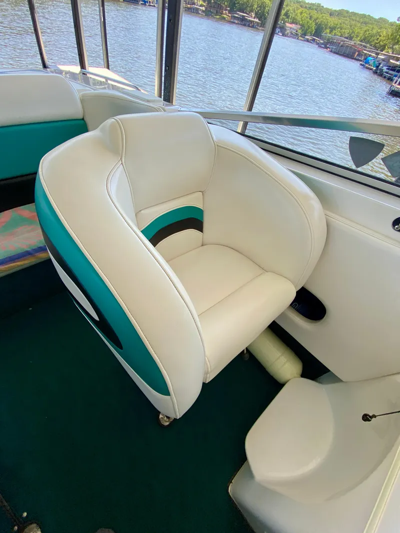 Slide: The Image of 1999 Checkmate 259 Convincer boat interior with white and teal seating by the water. - 18