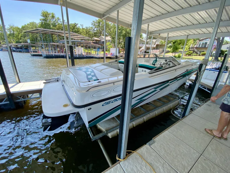 Slide: The Image of 1999 Checkmate 259 Convincer boat docked under a covered marina on a sunny day. - 2