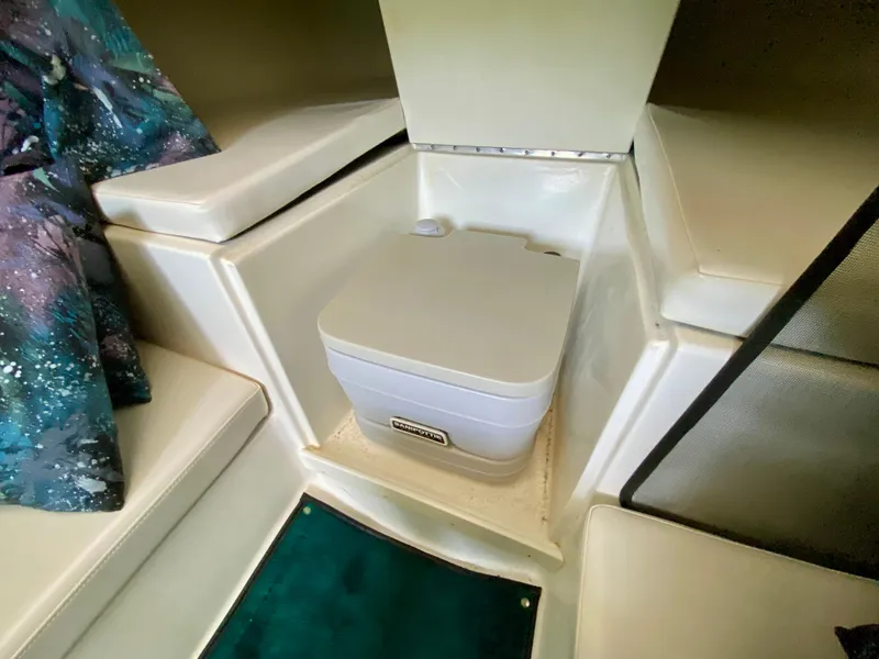 Slide: The Image of Interior of 1999 Checkmate 259 Convincer boat with portable toilet and seating area. - 27