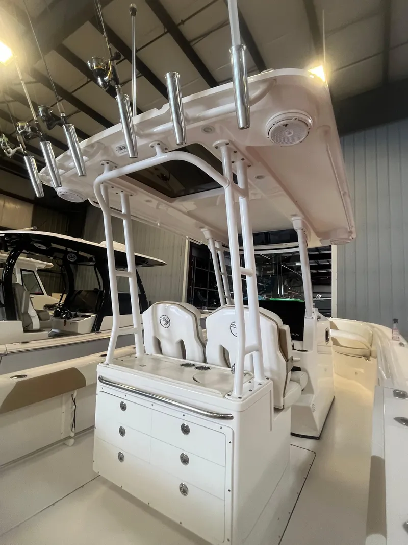 Slide: The Image of 2020 Edgewater 320CC boat interior with rod holders and seating in a showroom. - 12