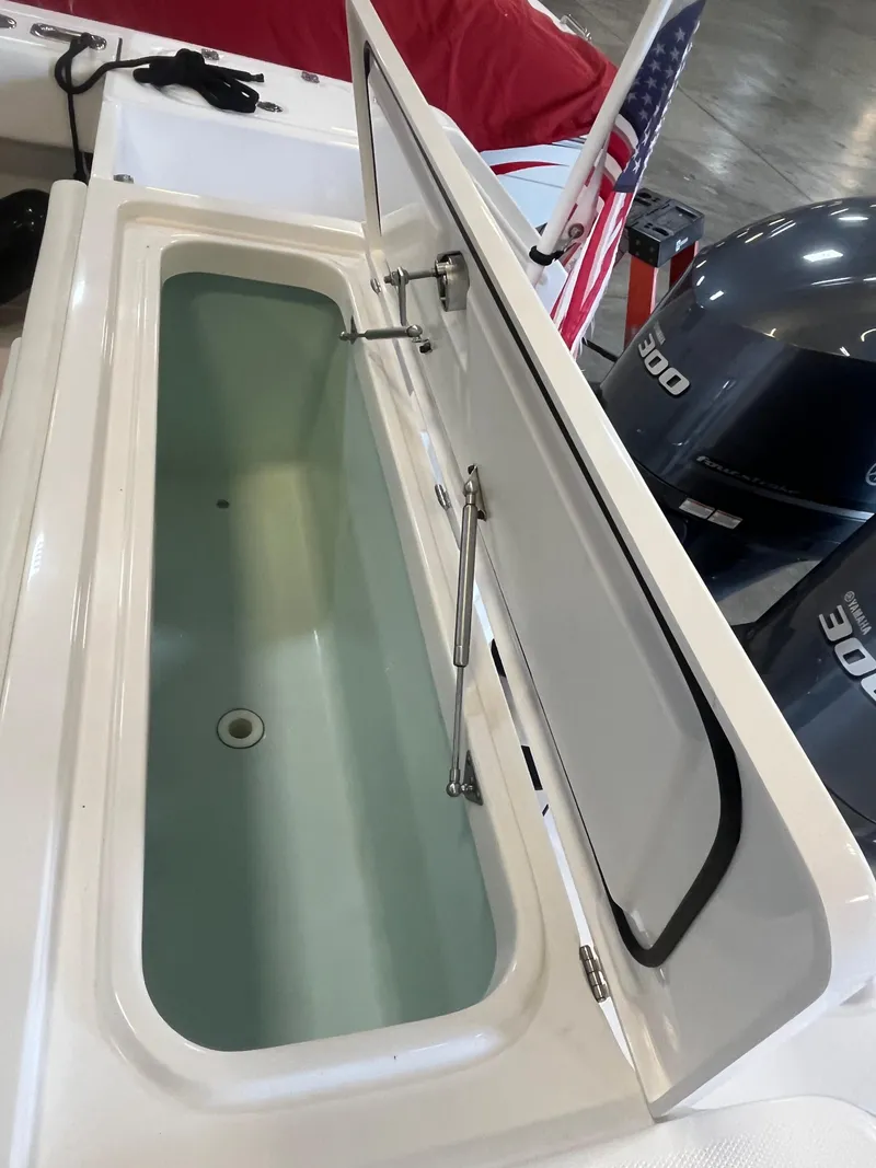 Slide: The Image of Open storage compartment on 2020 Edgewater 320CC boat with visible engine in background. - 21