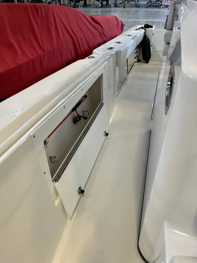 Slide: The Image of 2020 Edgewater 320CC boat interior with open storage compartment, red cover in background. - 9