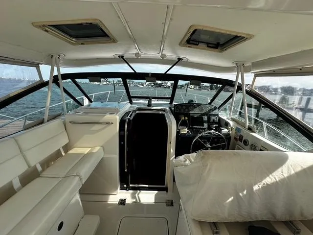 Slide: The Image of 2003 Tiara Yachts 3500 Express interior with white seating and marina view. - 5