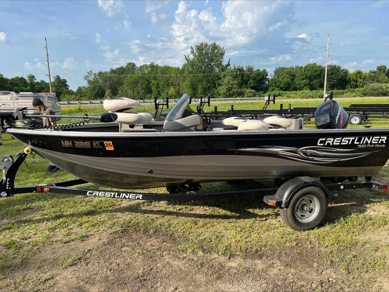Slide: The Image of 2009 Crestliner Fish Hawk 1600 SC boat on trailer, parked on grass under a blue sky. - 2