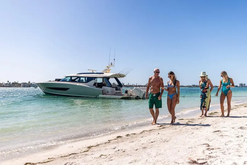 Slide: The Image of Beachgoers walking near a 2025 Scout 670 LXS yacht on a sunny day. - 11