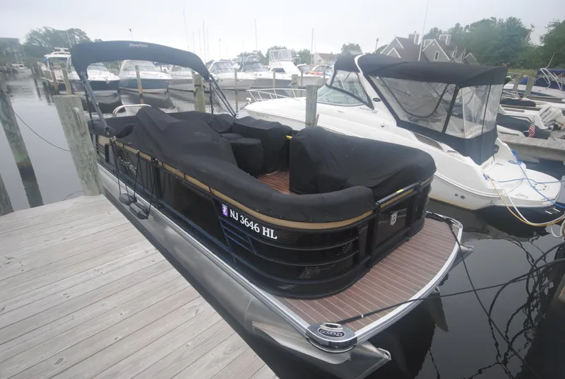Slide: The Image of 2018 Godfrey 255 ULB pontoon boat docked, covered, with nearby boats in marina. - 20