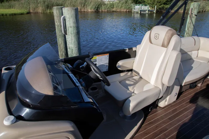 Slide: The Image of 2018 Godfrey 255 ULB boat interior with steering wheel and seating by the water. - 3
