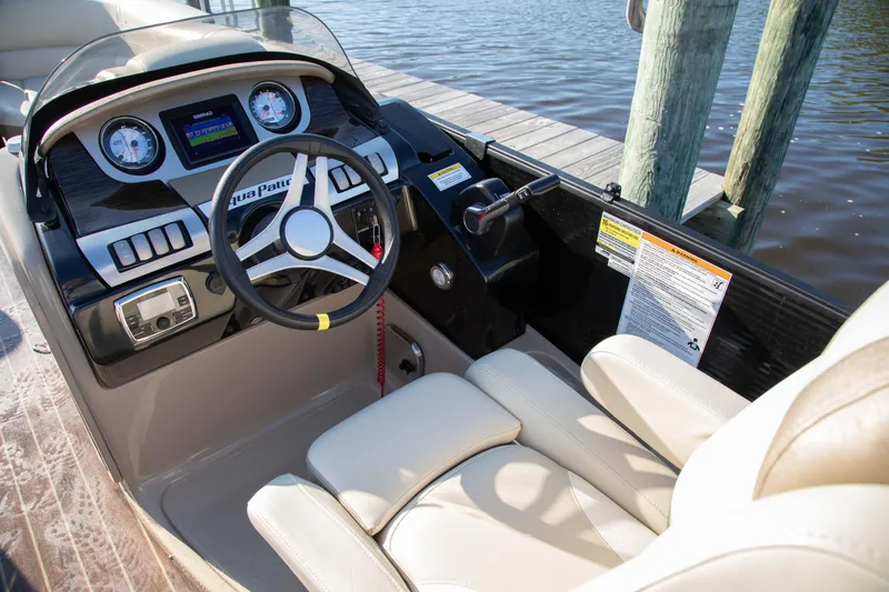 Slide: The Image of 2018 Godfrey 255 ULB boat cockpit with steering wheel and dashboard by the water. - 4
