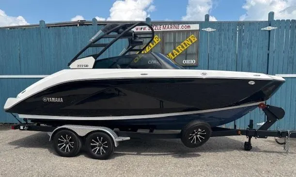 Slide: The Image of 2023 Yamaha Boats 222SD on trailer, sleek black and white design, parked outdoors. - 0