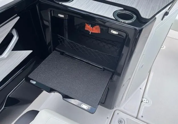 Slide: The Image of 2023 Yamaha Boats 222SD interior storage compartment with cup holders and fold-out tray. - 18