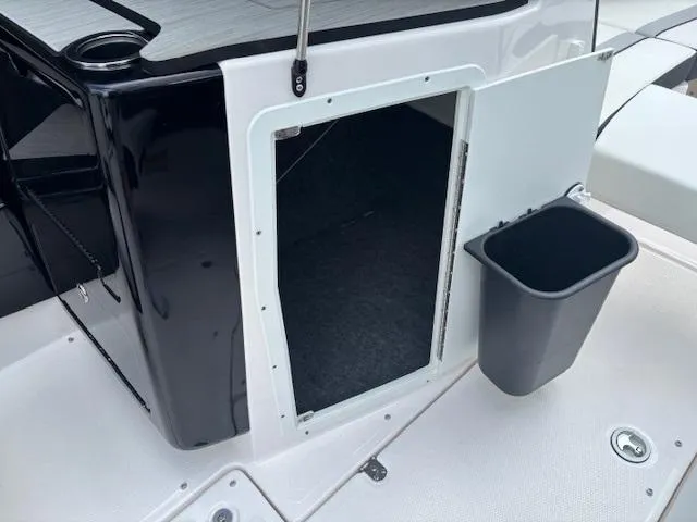 Slide: The Image of 2023 Yamaha Boats 222SD storage compartment with open door and trash bin. - 19