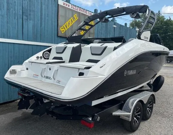 Slide: The Image of 2023 Yamaha Boats 222SD on trailer, sleek design, parked outdoors near blue fence. - 3