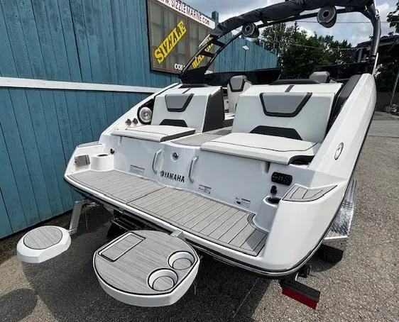 Slide: The Image of 2023 Yamaha Boats 222SD, sleek white design, rear seating, cup holders, docked outdoors. - 7