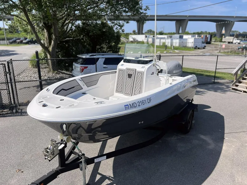 Slide: The Image of 2020 Wellcraft 182 Fishmaster boat on trailer, parked outdoors near a bridge. - 17