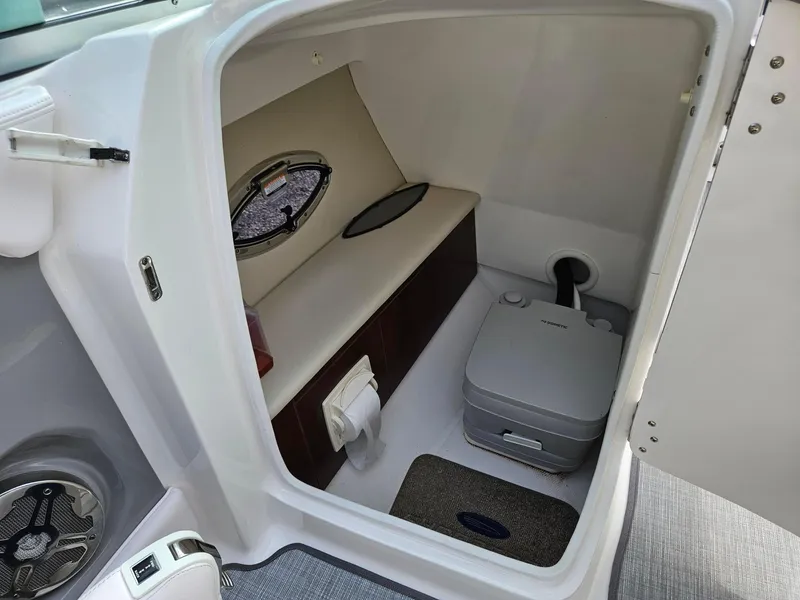 Slide: The Image of 2019 Chaparral 246 SSi boat interior with compact marine toilet and storage area. - 17